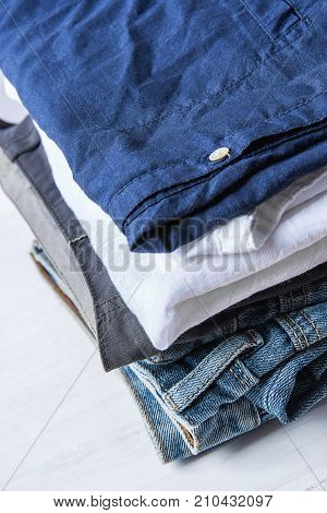 Stack Heap of Folded Jeans Cotton Pants and Shirts on White Wood Background Shelf Closet. Eco Fashion Authentic Classic Style. Natural Materials. Unisex.