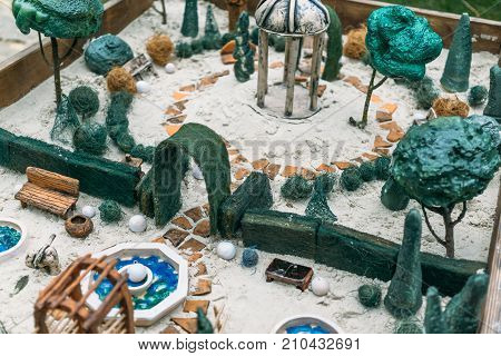 Miniature houses, toy landscape objects in sandbox. Anti-stress and soothing sand therapy. Landscape Layout