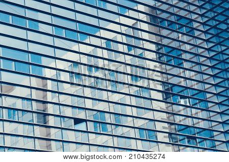 Abstract shot of glass transparent skyscraper office building with reflections for texture or background. Blue toned