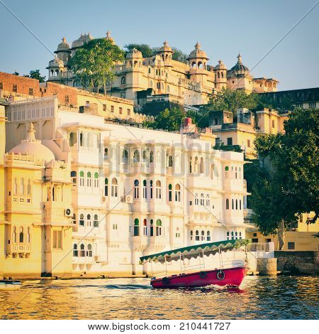 Water view of City Palace in Udaipur City Of Lakes in Rajastan, India. Red boat on Pichola Lake in Udaipur
