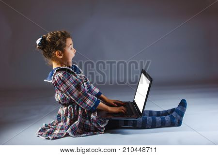 girl looking computer on a gray background surprise