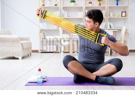 Young man exercising at home in sports and healthy lifestyle concept
