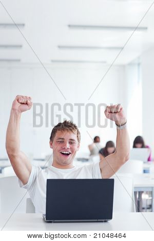 Ano! -šťastné mladé mužské vysokoškolský student, radost nad jeho úspěch při práci na jeho notebooku comp