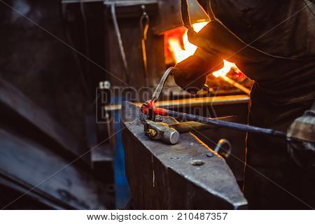 Blacksmith working on metal on anvil at forge high speed detail shot