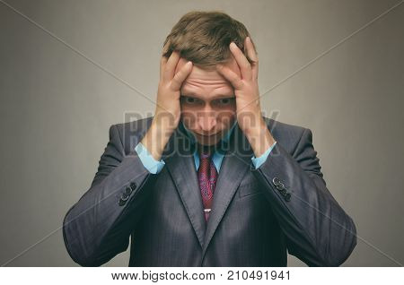 Business man in stress keeps his hands behind his head isolated. Debt. Stress situation.