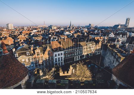 Ghent, Flanders, Belgium - December 30th, 2016. Gent Old town panoramic view from above Gravensteen castle. Ghent skyline with merchant houses roofs, St. Bavo and St.Jacob's cathedrals by golden hour.