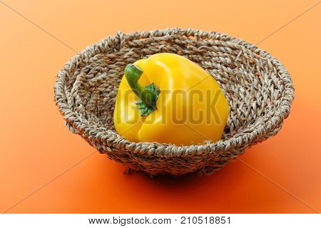 Beautiful of sweet yellow bell pepper isolated in basket on orange background.