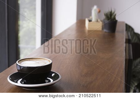 A cup of hot coffee on long wooden table with copy space.