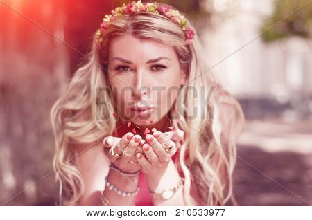 Young woman blowing heart shaped colorful confetti in air. Close up of woman in happy mood with confetti all around.