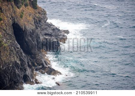 View from mountains to blue sea. Water smashing rocks. Monterosso al Mare, Cinque Terre, Italy