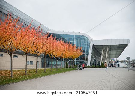 trees with yellow leaves near modern glass airport people walkin near by
