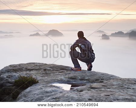 Tourist Sit On Peak Of Sandstone Rock And Watching Into Colorful Mist And Fog In  Morning Valley. Sa