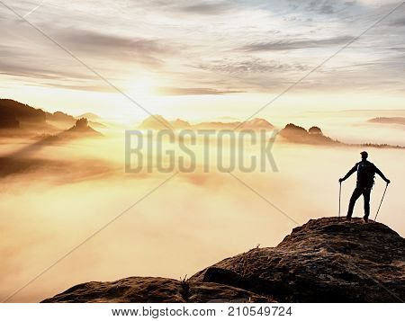 Man Silhouette With Poles In Hand. Sunny Spring Daybreak And Tourist Guide Stay On Sharp Cliff Of Mo