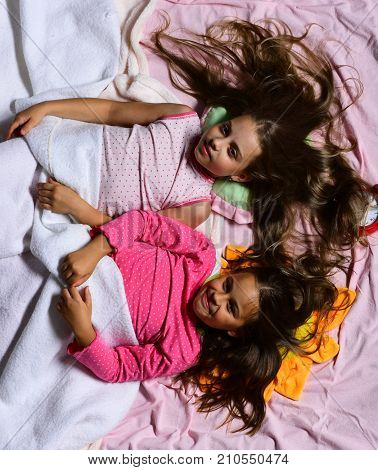 Schoolgirls In Pink Pajamas Wallow On Colorful Pillows, Top View