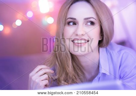 Being cheerful. Pretty dark-eyed young woman smiling and feeling happy and her eyes shining