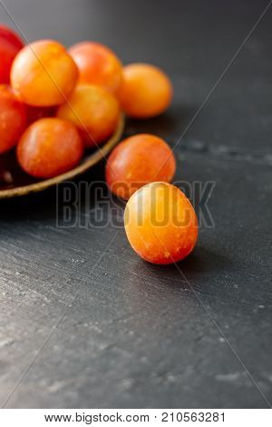 whild ripe plums on black stone surface.
