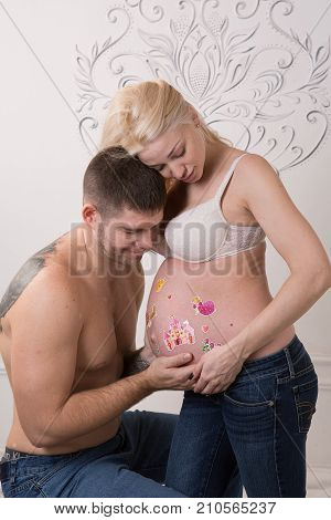 Beautiful pregnant couple in love on the background. Hands of husband on the tummy of his pregnant wife. Young man tenderly stroked pregnant belly of his wife. Husband kissing pregnant belly.