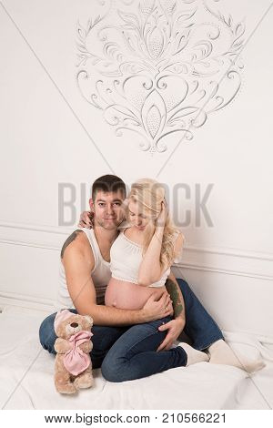 Beautiful pregnant couple in love on the background. Hands of husband on the tummy of his pregnant wife. Young man tenderly stroked pregnant belly of his wife. Husband kissing pregnant belly.