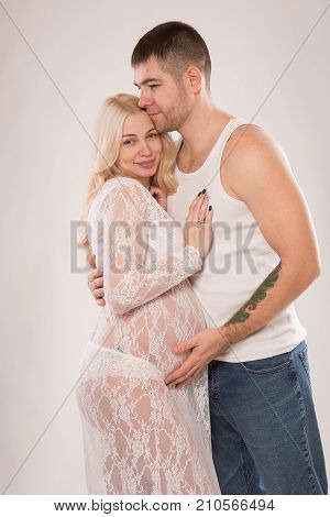 Beautiful pregnant couple in love on the background. Hands of husband on the tummy of his pregnant wife. Young man tenderly stroked pregnant belly of his wife. Husband kissing pregnant belly.