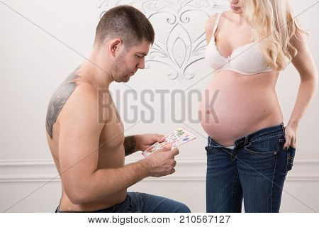 Beautiful pregnant couple in love on the background. Hands of husband on the tummy of his pregnant wife. Young man tenderly stroked pregnant belly of his wife. Husband kissing pregnant belly.
