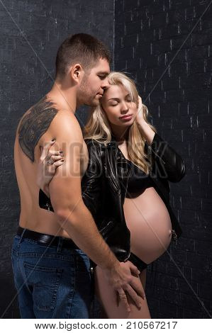 Beautiful pregnant couple in love on the background. Hands of husband on the tummy of his pregnant wife. Young man tenderly stroked pregnant belly of his wife. Husband kissing pregnant belly.