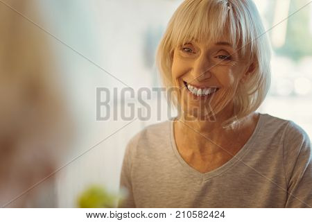 Wonderful time. Cheerful delighted elderly woman smiling and feeling happy while enjoying her day