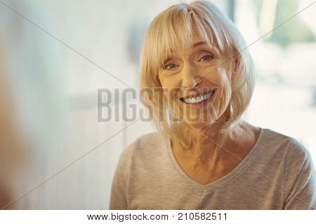 Positive emotions. Portrait of a delighted positive elderly woman smiling and looking at you while expressing her positive emotions