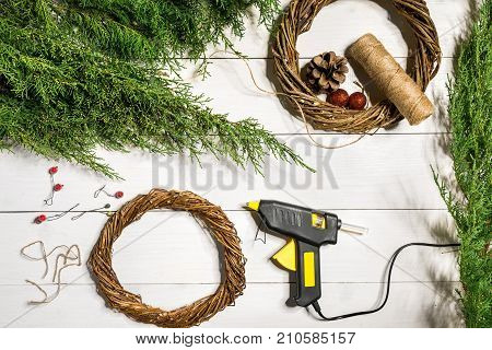 Make a Christmas wreath with your own hands. Spruce branch, Christmas wreath and gifts on a white wooden background. Workplace for preparing handmade decorations. Christmas and New year