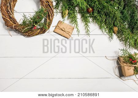 Make a Christmas wreath with your own hands. Spruce branch, Christmas wreath and gifts on a white wooden background. Workplace for preparing handmade decorations. Christmas and New year