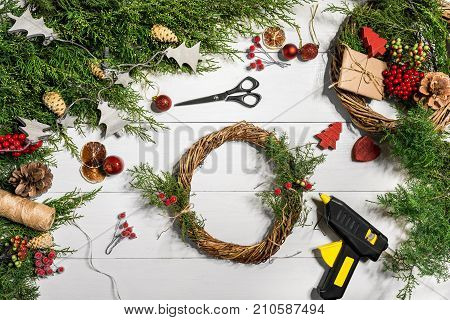 Make a Christmas wreath with your own hands. Spruce branch, Christmas wreath and gifts on a white wooden background. Workplace for preparing handmade decorations. Christmas and New year