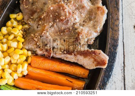 Pork steak with vegetable. Corn carrots green beans on wooden table background.