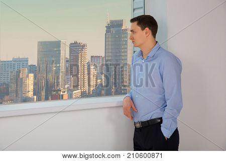 Portrait of businessman. Man look to the window to skyscrapers