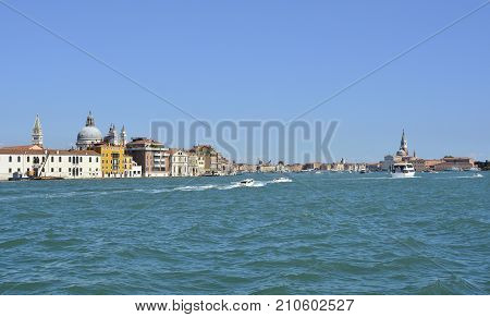 A view of the island of Dorsodoro in Venice taken from the island of Giudecca across the Giudecca Canal. The iconic Campanile di San Marco (Saint Mark's Belltower) and the church of Santa Maria Della Salute (Saint Mary of Health) can be seen towering abov