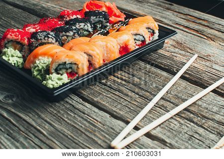 On A Wooden Table In The Black Container Are Nicely Decomposition Sushi