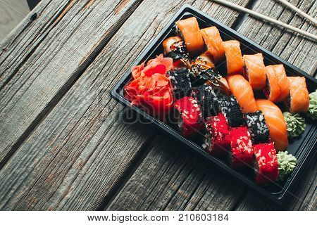 On A Wooden Table In The Black Container Are Nicely Decomposition Sushi