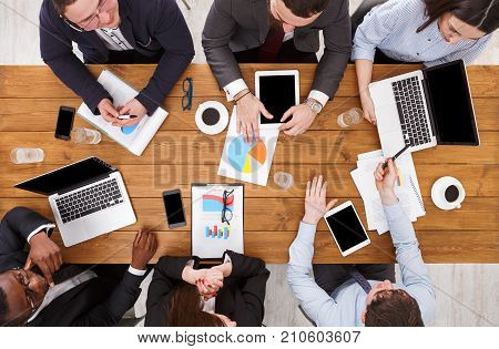 Multiethnic team meeting. Manager and emploees, development strategy, top view of wooden table
