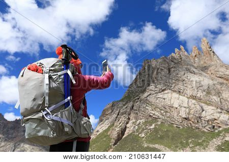 successful woman hiker use smartphone in mountain top rock