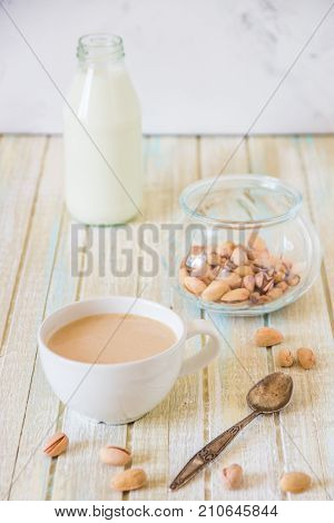 Coffee With Milk And Pistachios On Wooden Table