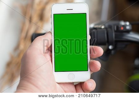 Man's hand use smartphone while he stands near by the road with bicycle. Green screen