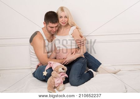 Beautiful pregnant couple in love on the background. Hands of husband on the tummy of his pregnant wife. Young man tenderly stroked pregnant belly of his wife. Husband kissing pregnant belly.