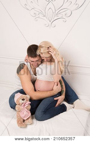 Beautiful pregnant couple in love on the background. Hands of husband on the tummy of his pregnant wife. Young man tenderly stroked pregnant belly of his wife. Husband kissing pregnant belly.