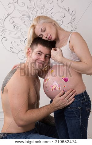 Beautiful pregnant couple in love on the background. Hands of husband on the tummy of his pregnant wife. Young man tenderly stroked pregnant belly of his wife. Husband kissing pregnant belly.