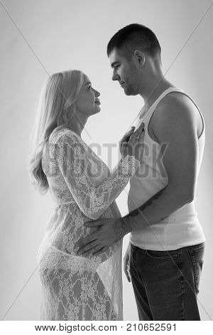 Beautiful pregnant couple in love on the background. Hands of husband on the tummy of his pregnant wife. Young man tenderly stroked pregnant belly of his wife. Husband kissing pregnant belly.