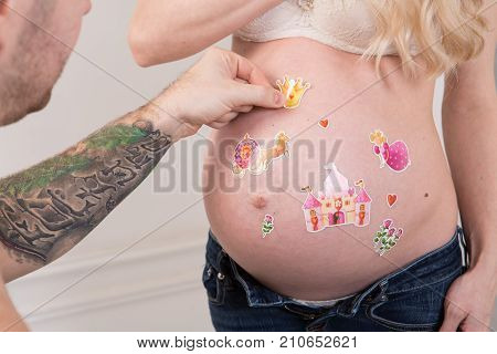 Beautiful pregnant couple in love on the background. Hands of husband on the tummy of his pregnant wife. Young man tenderly stroked pregnant belly of his wife. Husband kissing pregnant belly.