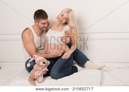Beautiful pregnant couple in love on the background. Hands of husband on the tummy of his pregnant wife. Young man tenderly stroked pregnant belly of his wife. Husband kissing pregnant belly.