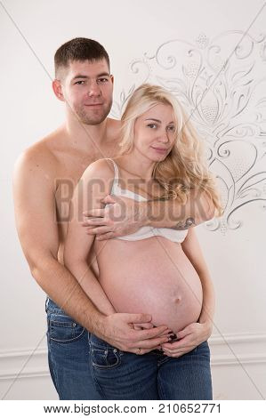 Beautiful pregnant couple in love on the background. Hands of husband on the tummy of his pregnant wife. Young man tenderly stroked pregnant belly of his wife. Husband kissing pregnant belly.