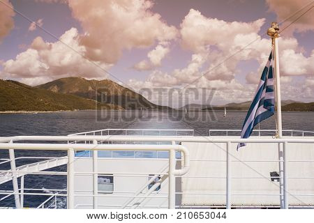 The Greek flag on the ship against the background of the sea of islands and opposite the ships. Sea voyage in the Ionian sea.