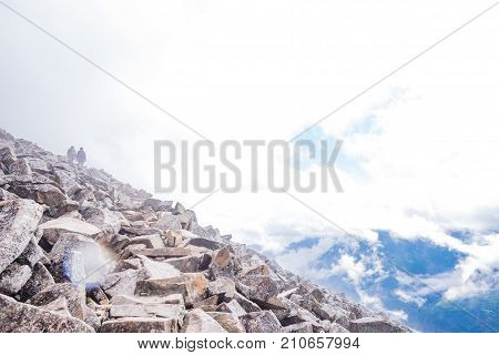 Hiking into an abyss of clouds - hikers in the distance - rocks in front - space for text