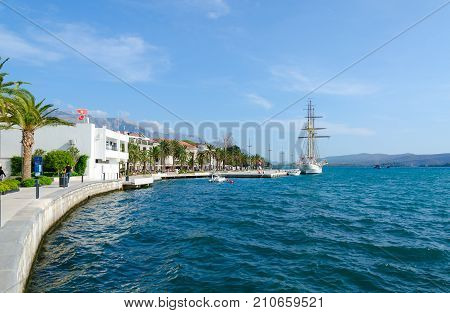TIVAT MONTENEGRO - SEPTEMBER 10 2017: Sailboat near seafront of popular resort town of Tivat Montenegro. Unidentified people are strolling along promenade