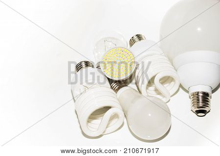 Several different led bulbs and compact fluorescent lamps with the size of the male screw base E27 on a light background